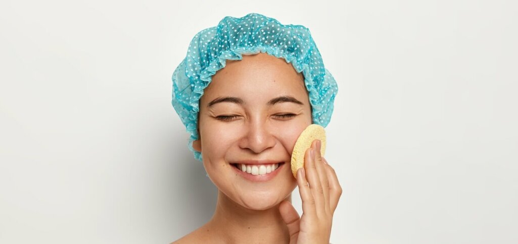 portrait of happy looking smiling lady uses cosmetic sponge for cleaning face