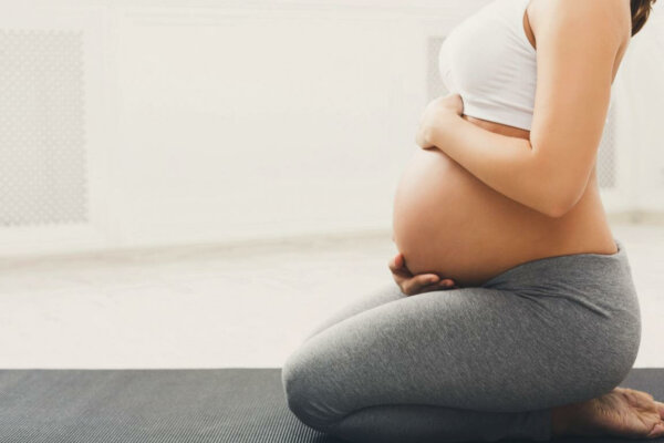 pregnant woman training yoga in hero pose