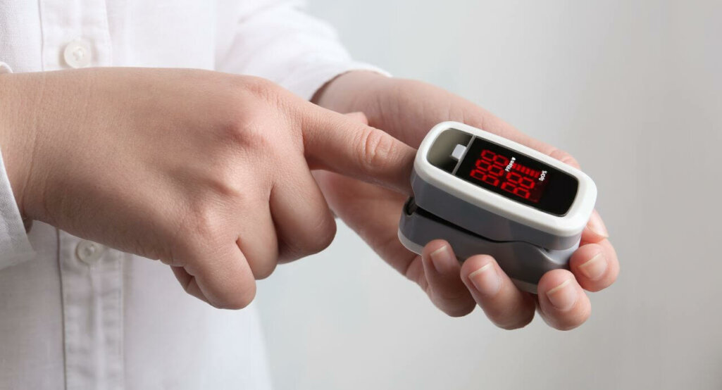 Woman using modern fingertip pulse oximeter