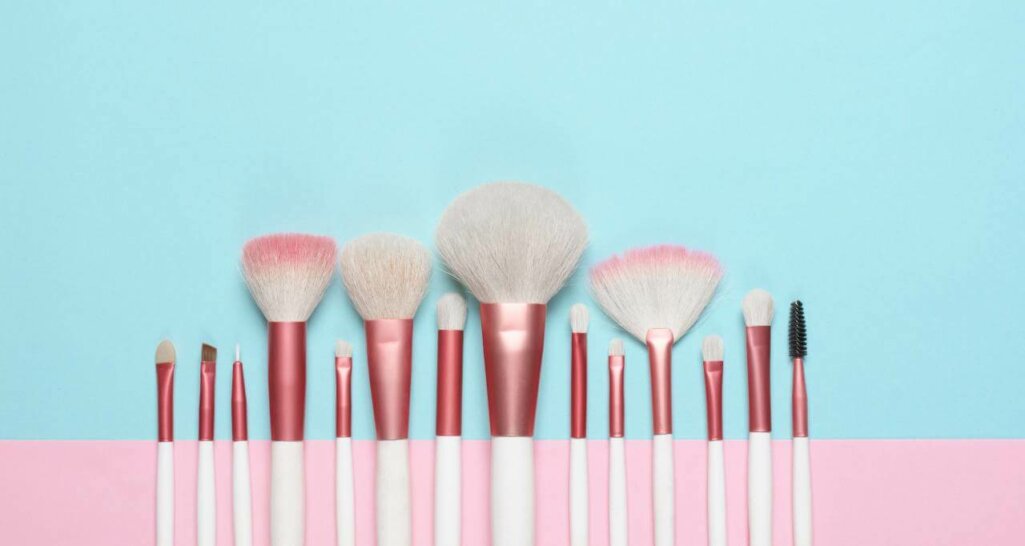 Set of makeup brushes on pink and aqua colored composed background.