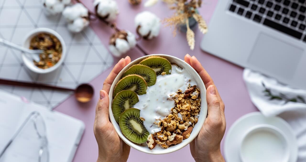 Female hand holding healthy breakfast bowl over work table 
