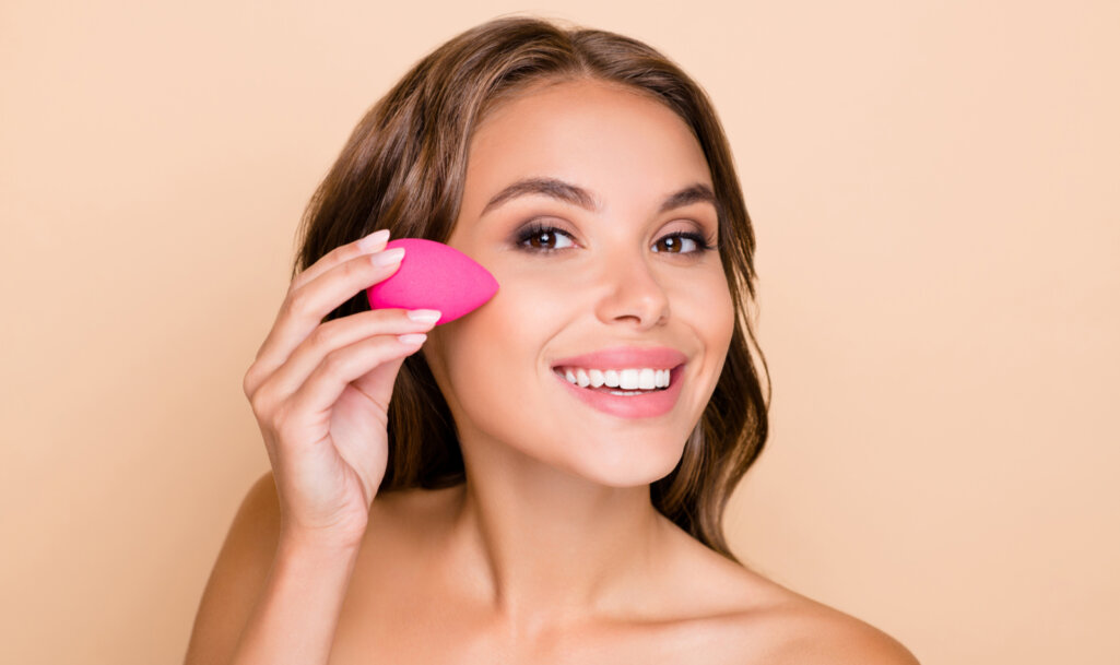 Photo of young beautiful smiling woman applying foundation