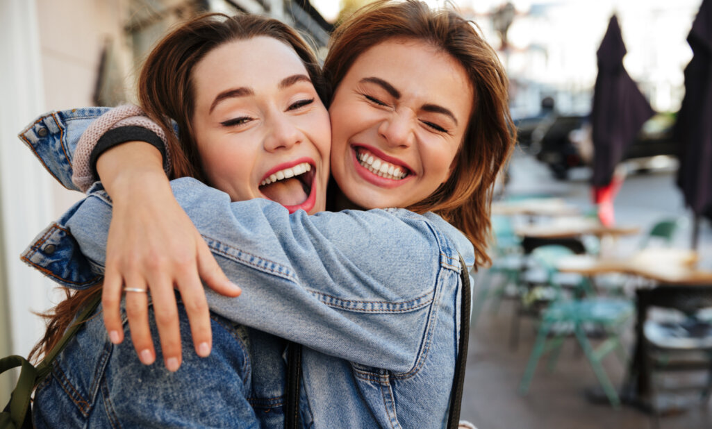 Κοντινή φωτογραφία των φίλων της γυναίκας που γελάει αγκαλιάζει ο ένας τον άλλο στο δρόμο της πόλης