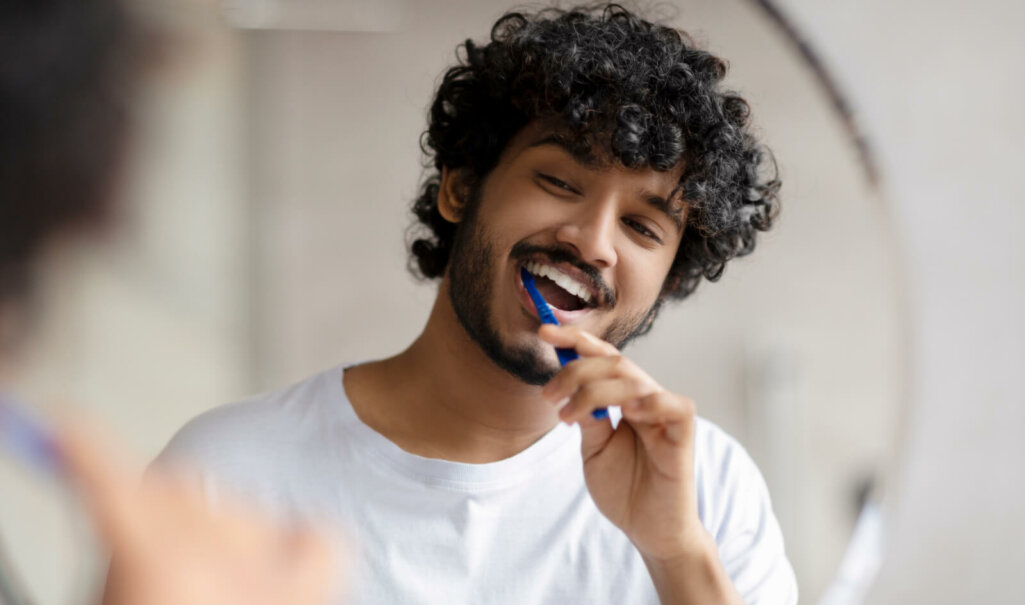 Oral care concept. Young indian man cleaning teeth with toothbrush