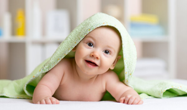 Smiling baby boy after shower or bath with towel on head