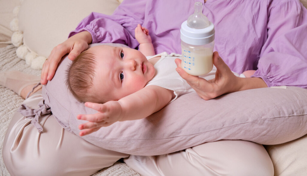 Woman mother feeds infant baby formula from a bottle