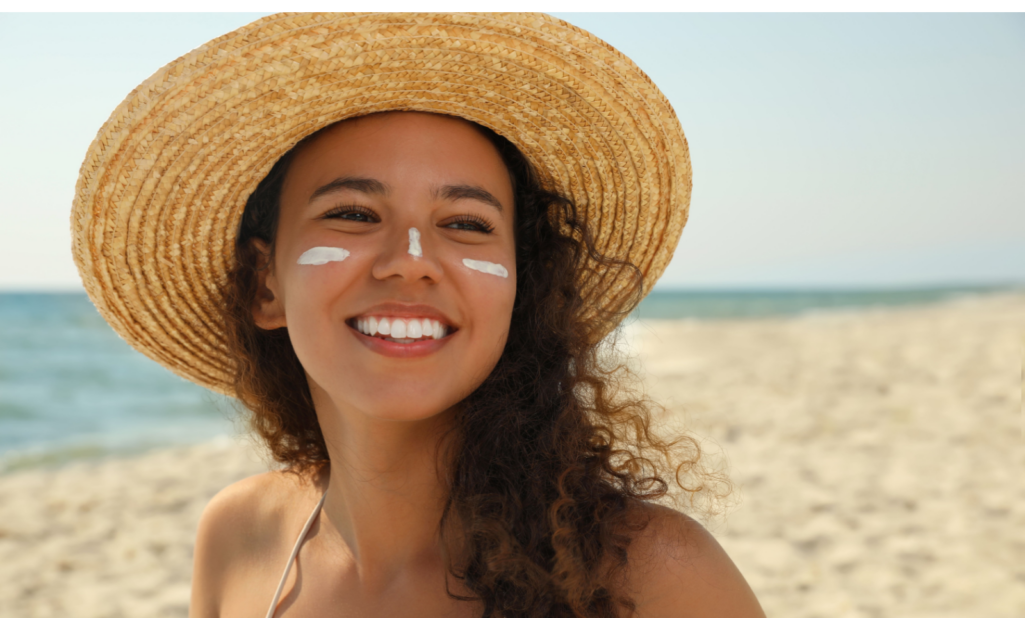 Beautiful African American woman with sun protection cream on face at beach