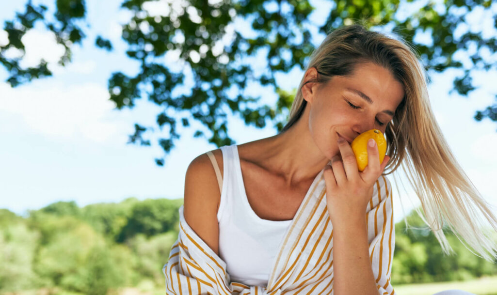 Candid portrait of a gorgeous blonde young woman enjoying smells of lemon