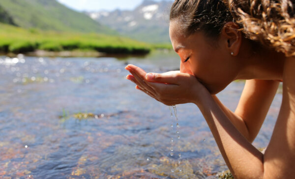 Side view portrait of a woman drinking raw water from river