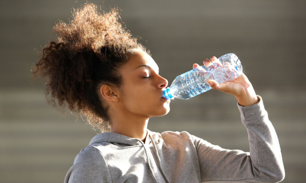 Κοντινό πορτρέτο μιας ελκυστικής νεαρής γυναίκας πόσιμο νερό από το μπουκάλι