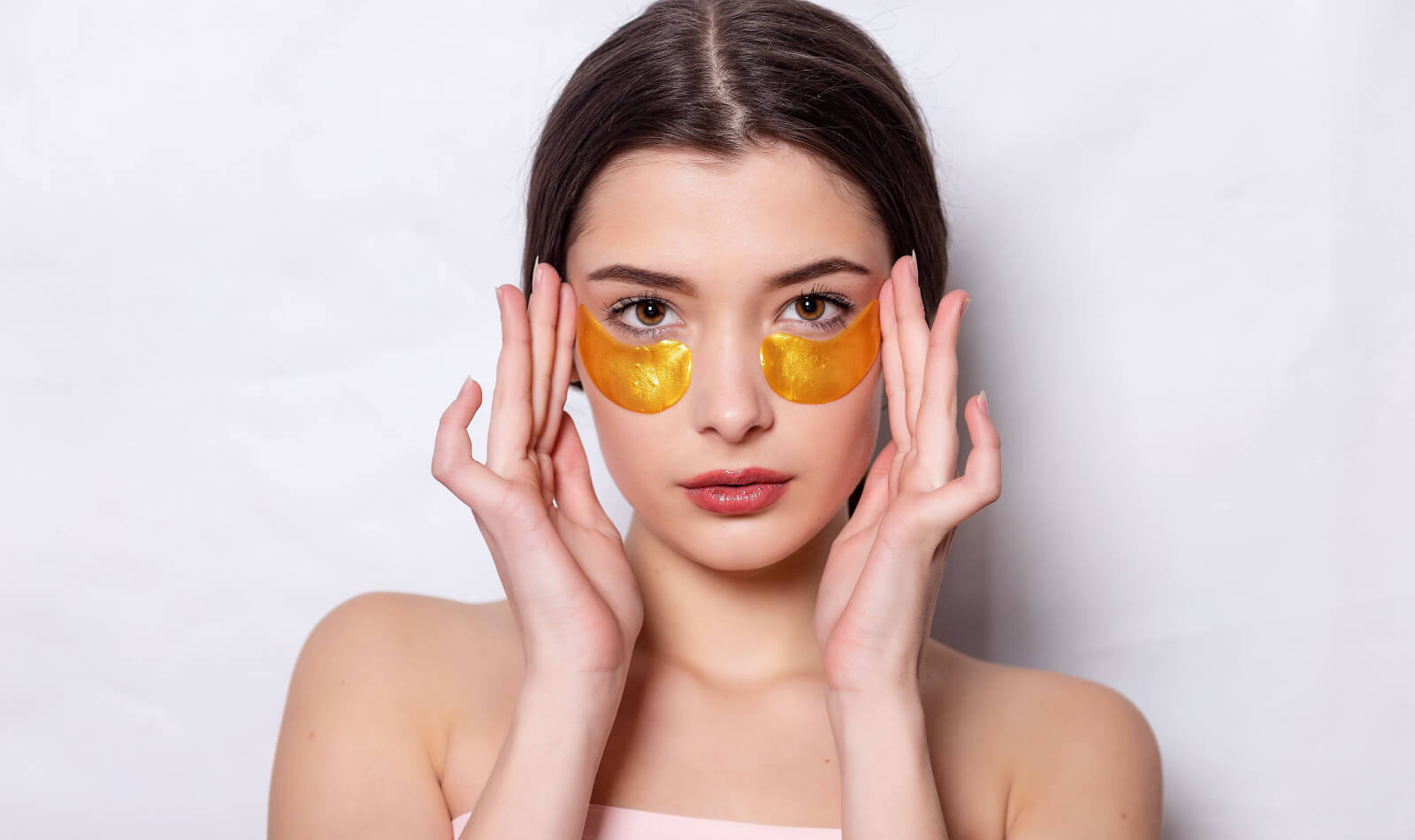 Woman with under eye collagen gold pads, beauty model girl face with healthy fresh skin.