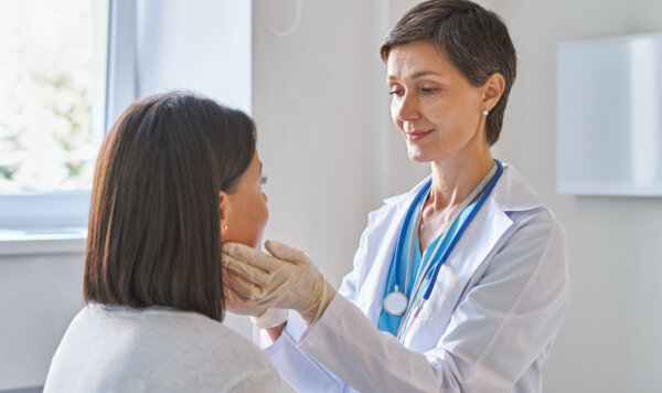 Γυναίκα ιατρός που είναι ενδοκρινολόγος εξετάζει τους αδένες γυναίκας ασθενούς για την πιθανότητα θυρεοειδούς.