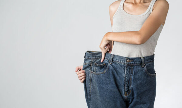 Weight loss woman with old jeans, isolated on background