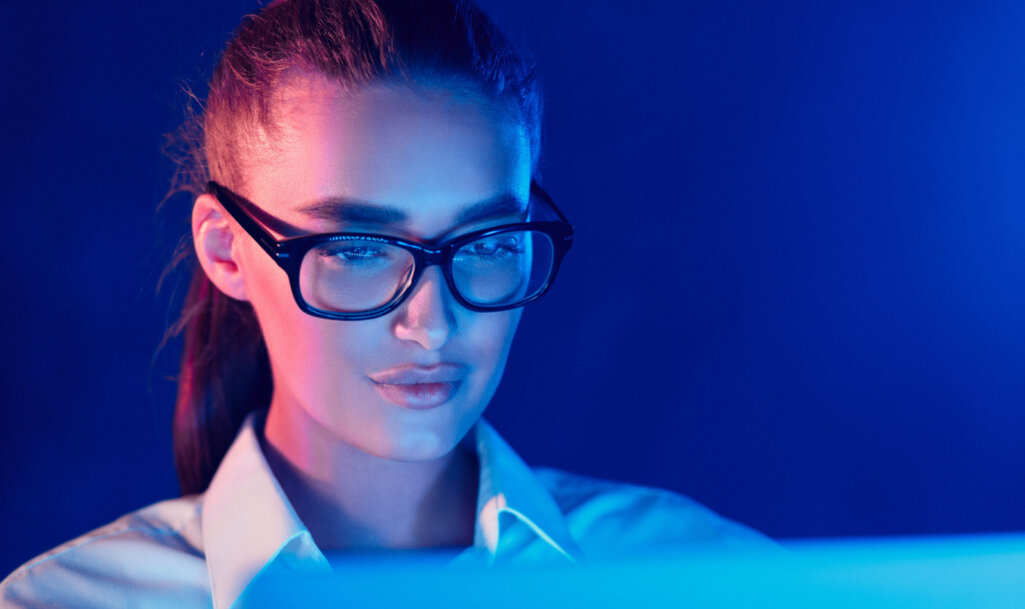 Νυχτερινή Online Εργασία Γυναίκα σε γυαλιά χρησιμοποιώντας φορητό υπολογιστή σε πολύχρωμα φώτα νέον