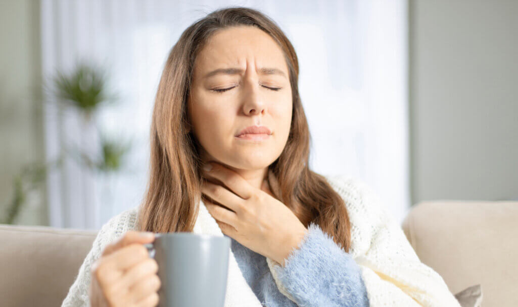 Νεαρή γυναίκα πάσχει από πονόλαιμο και αντιμετωπίζει τα συμπτώματα με ζεστό τσάι