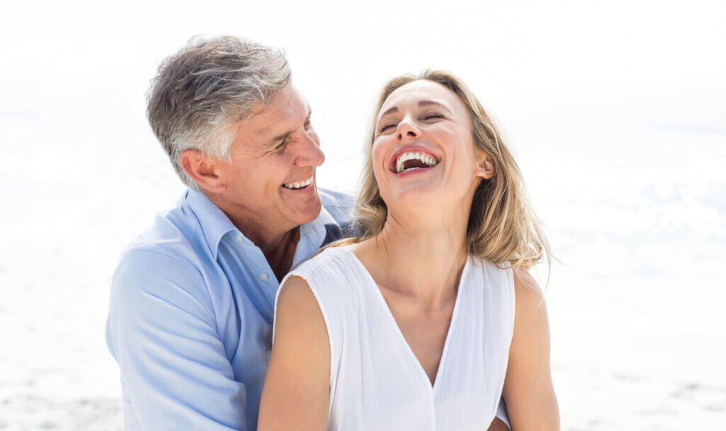 Ευτυχισμένο ζευγάρι να γελάει μαζί στην παραλία. Κόνσεπτ πρόληψης του καρκίνου του παχέος εντέρου με self test