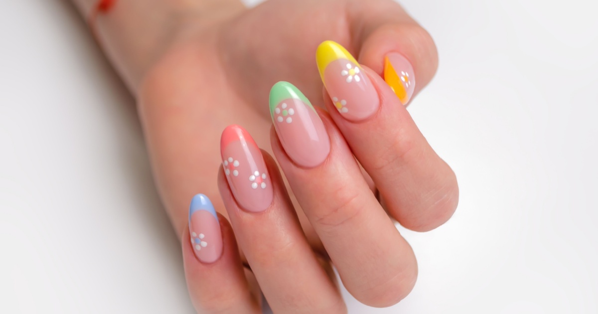 Hands of a young woman with a manicure. The nails are covered with gel polish with colored French and flowers